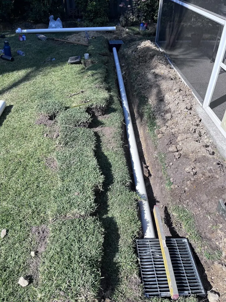 New drain line and channel grate installed across a Gold Coast lawn