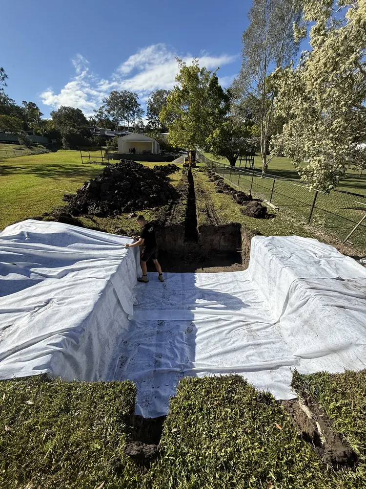 Trench lined with geotextile fabric for subsoil drainage on a Gold Coast backyard