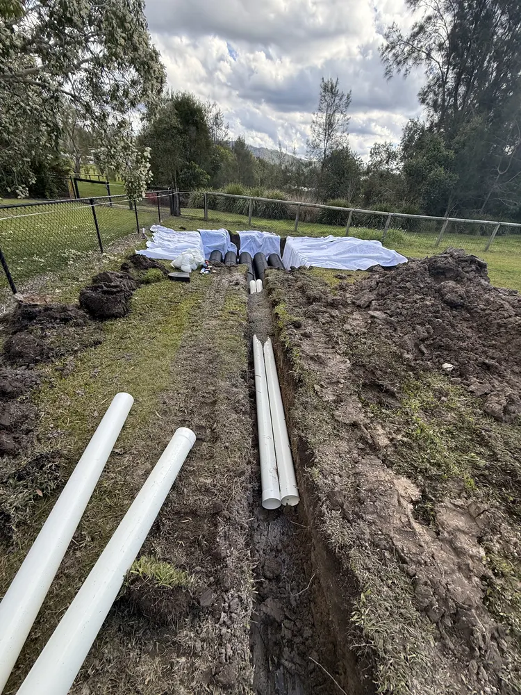 PVC stormwater pipes laid out beside the drainage trench