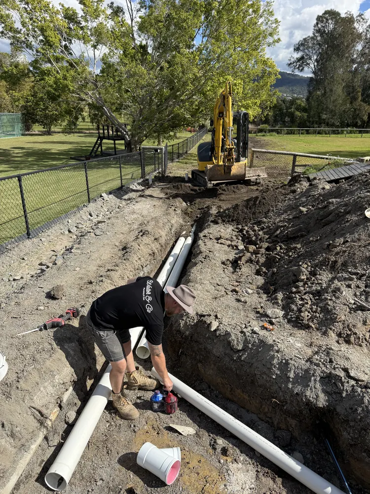 Fitting PVC drainage pipe in the trench at the Oxenford job
